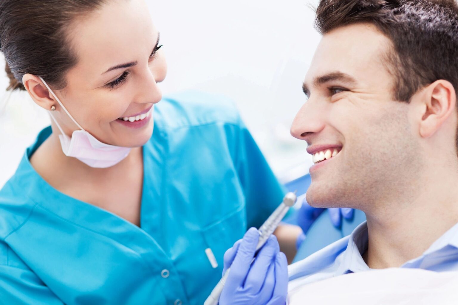 Smiling dentist examining a patient's teeth.