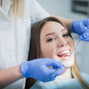 Beautiful happy brunette girl geeting her teeth examined. Dentist office
