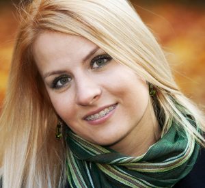 Portrait of smiling young blond woman over yellow autumn leaves, 25-30 years old