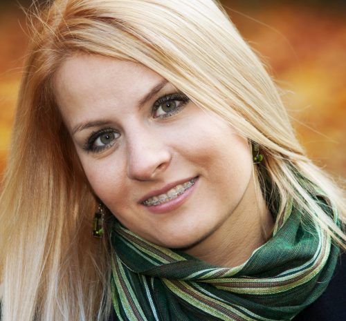 Portrait of smiling young blond woman over yellow autumn leaves, 25-30 years old